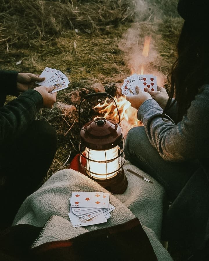 Playing cards by a campfire lantern